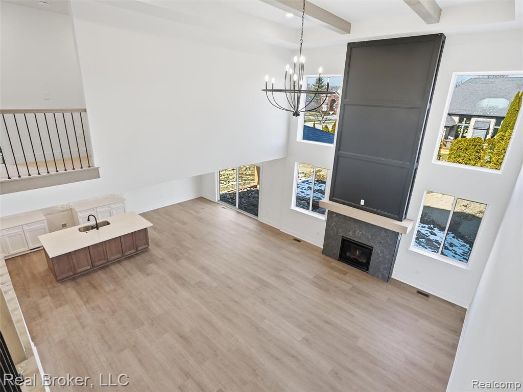 Unfurnished living room with a fireplace, light wood-style floors, and suspended lighting