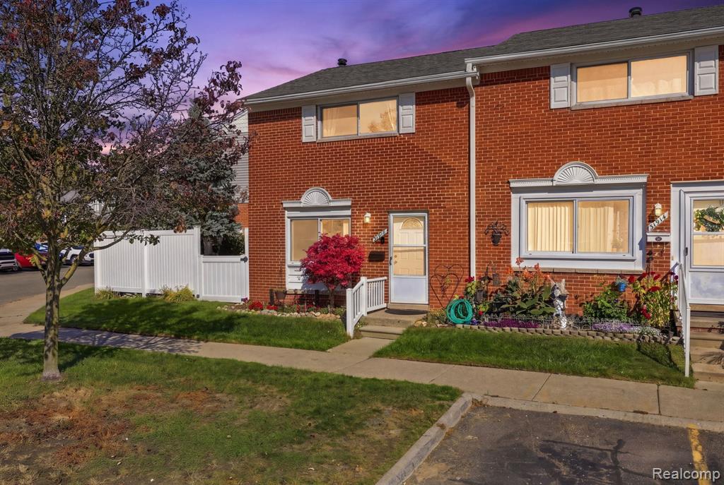 Multi-level brick exterior featuring arched window detailing, light-toned window frames, and white vinyl privacy fencing