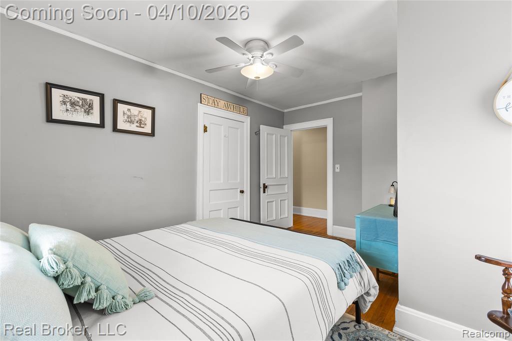 Bedroom with crown molding, wood finished floors, and a ceiling fan