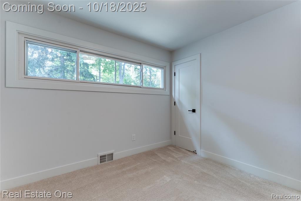 Carpeted spare room featuring baseboards