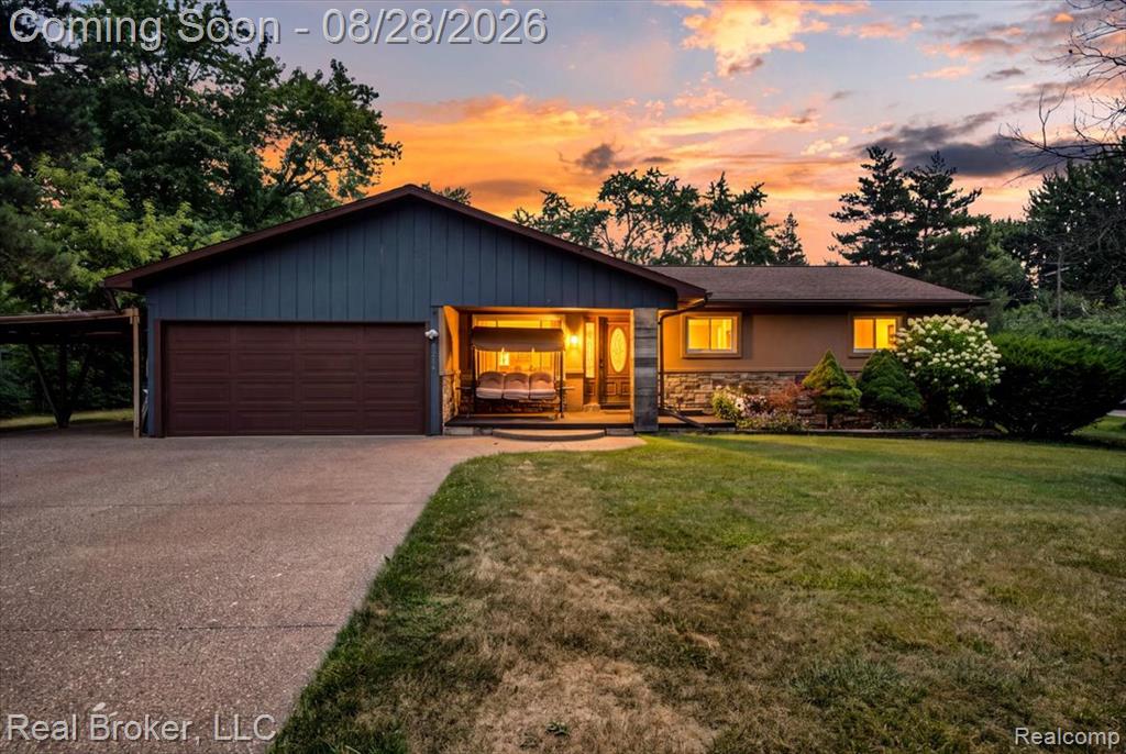 Ranch-style exterior with a two-car garage, covered carport, and stone facade accents