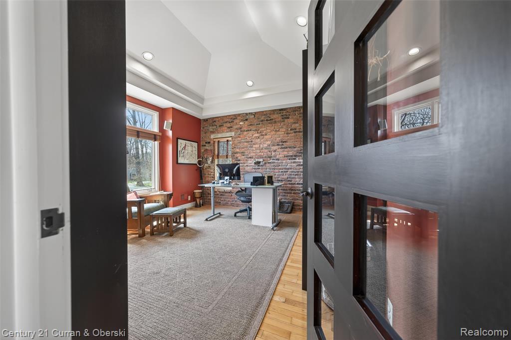 Home office featuring brick wall, light wood finished floors, and recessed lighting