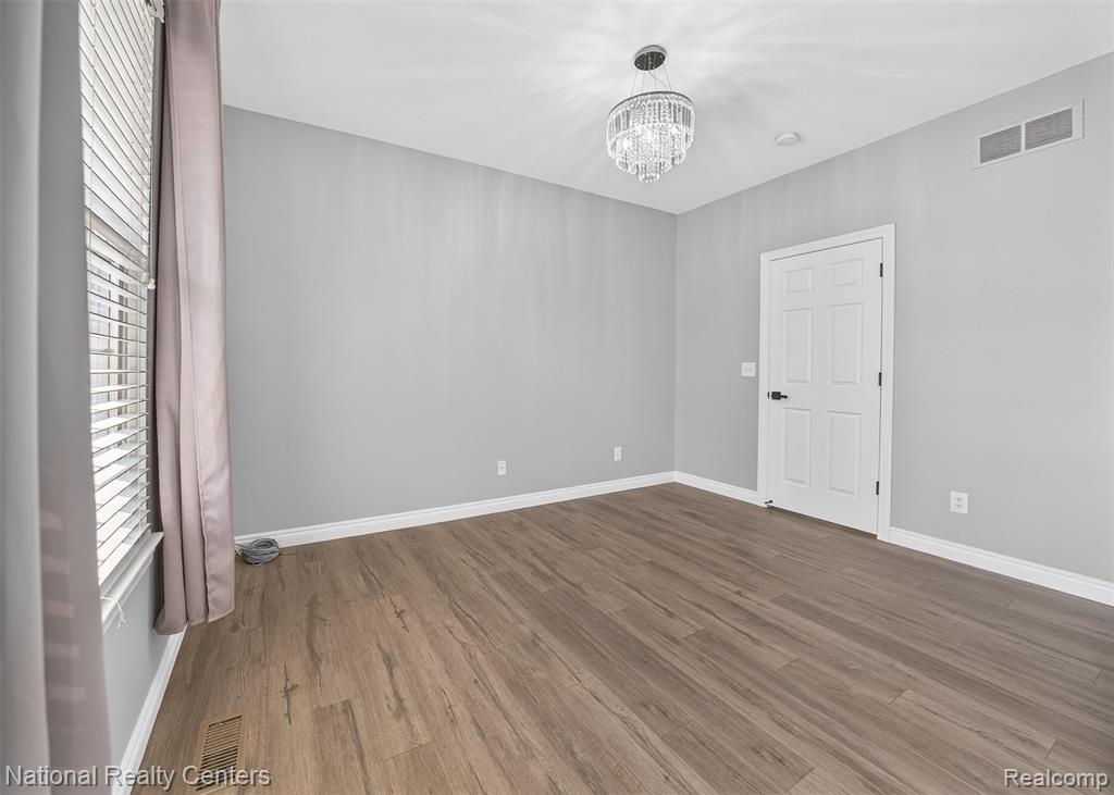 Unfurnished room featuring hanging lights and wood finished floors