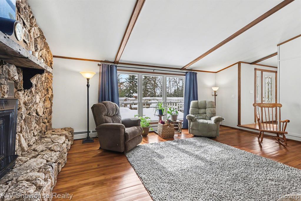 Living room featuring a fireplace, dark wood-type flooring, and a baseboard heating unit