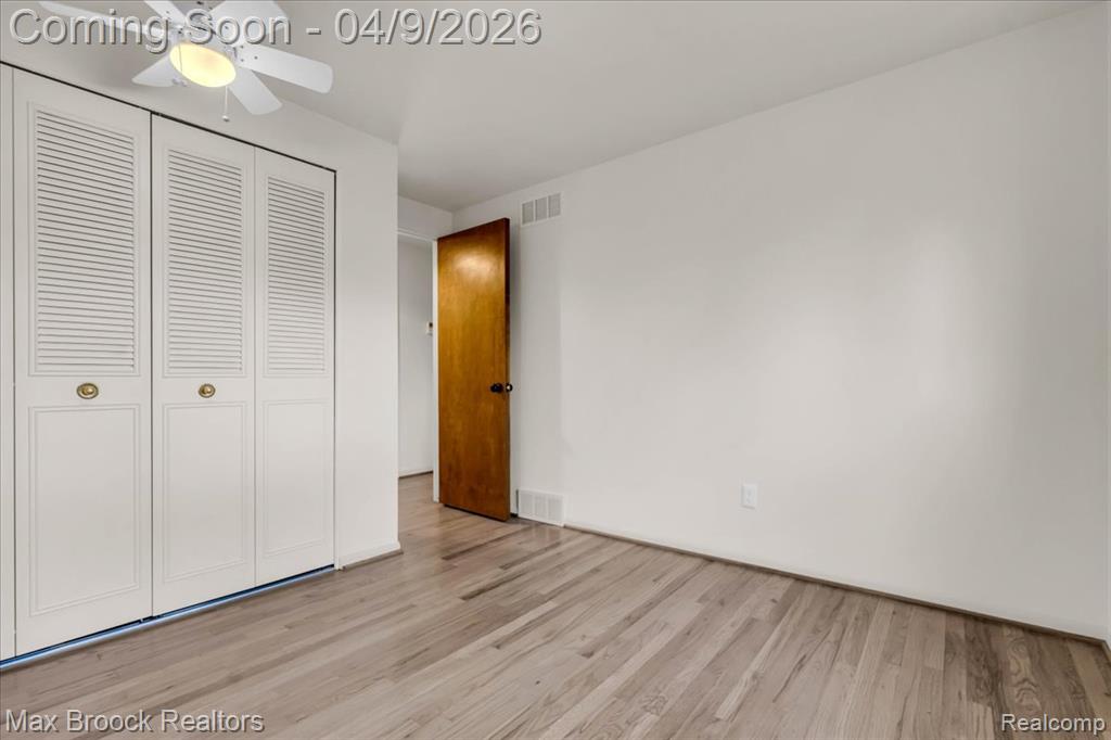 Unfurnished bedroom with light wood-style flooring, a closet, and a ceiling fan
