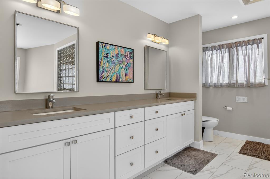 Bathroom featuring double vanity and light marble finish flooring