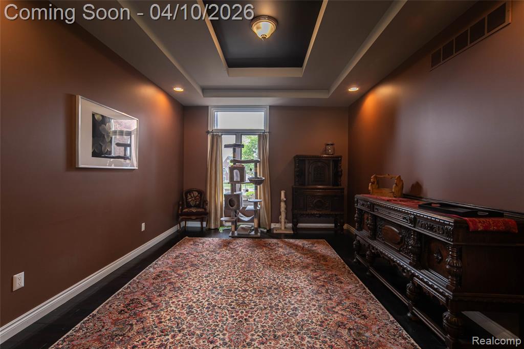 Sitting room with recessed lighting, a tray ceiling, and dark wood-style flooring