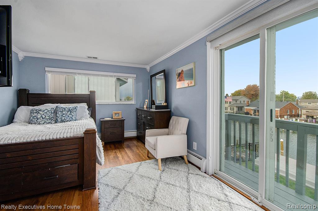Bedroom with access to outside, dark wood-type flooring, a baseboard heating unit, crown molding, and baseboard heating