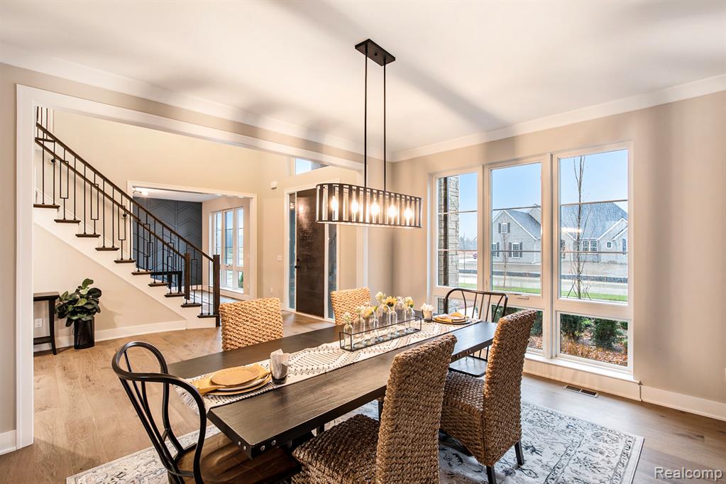 Dining room featuring stairway, wood finished floors, healthy amount of natural light, ornamental molding, and a chandelier