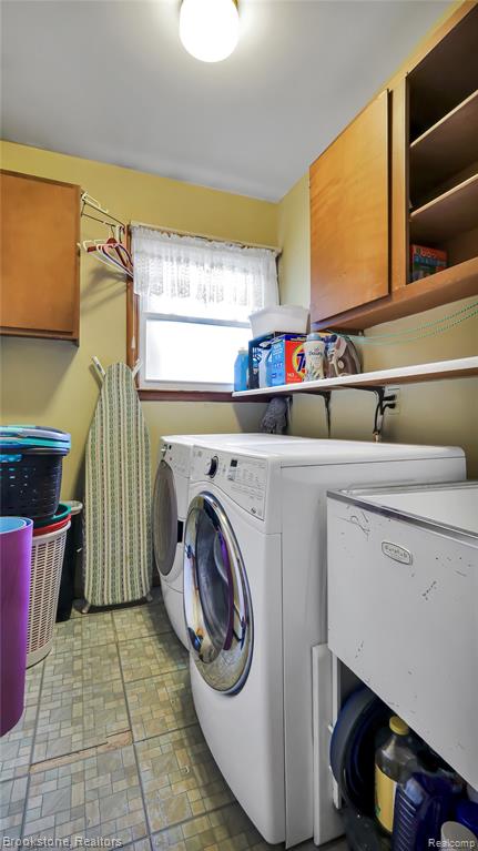 Laundry room with cabinet space, brick patterned flooring, and washer and dryer