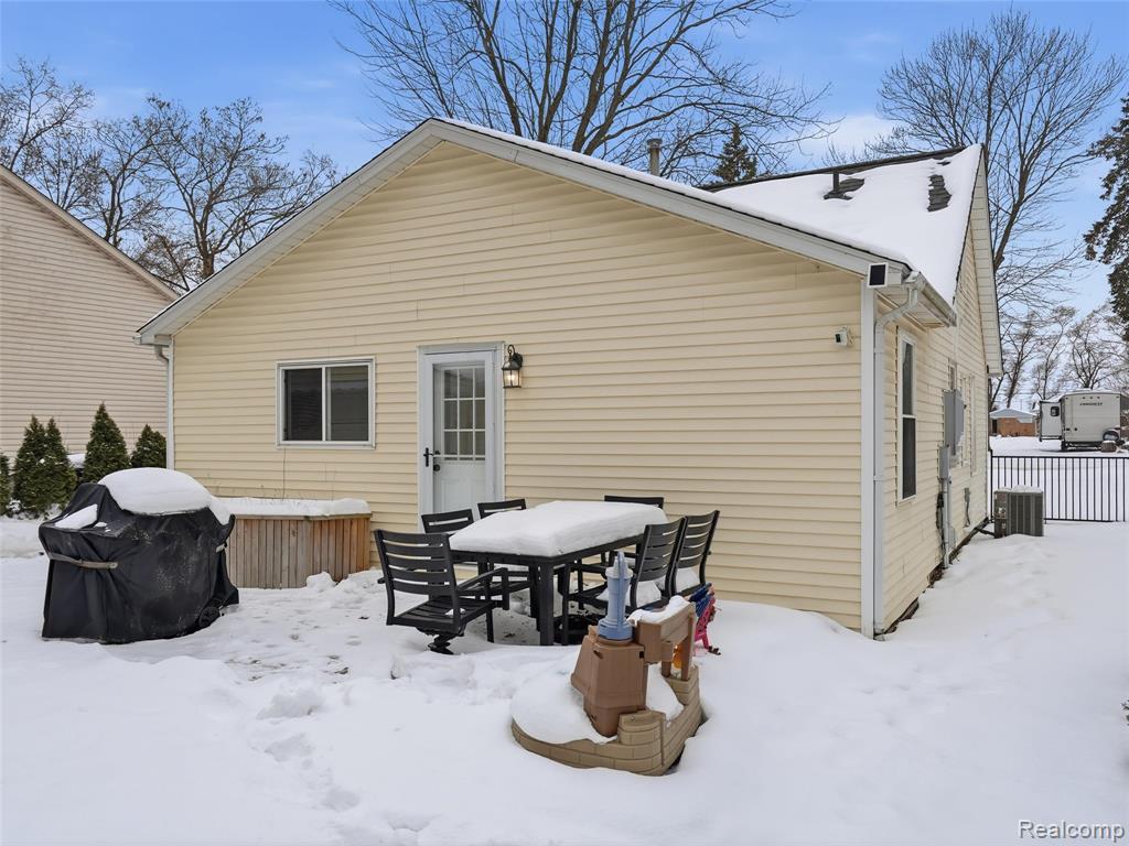 Snow covered back of property featuring outdoor dining area