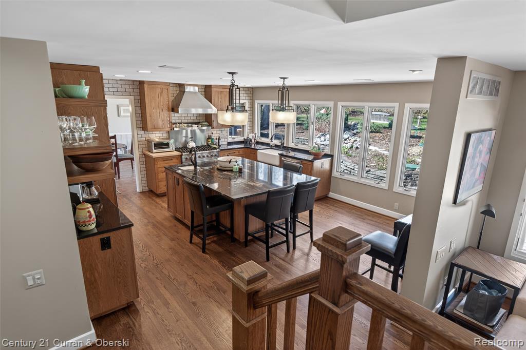 Kitchen with a center island, pendant lighting, wood finish cabinets, dark wood-style floors, and a breakfast bar area