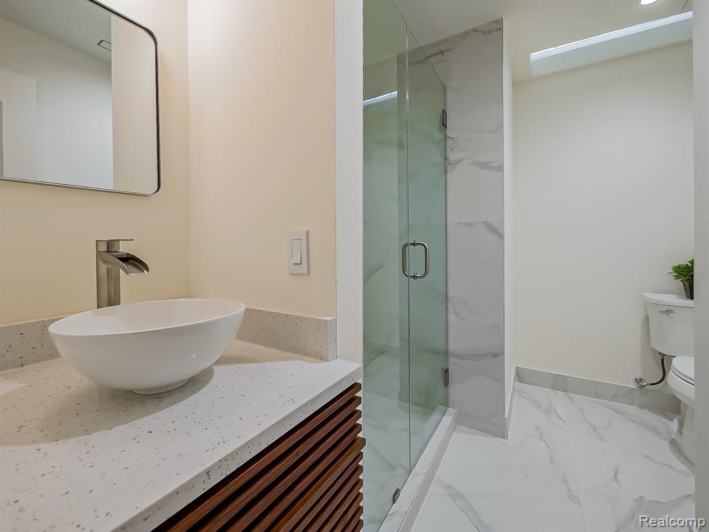 Full bathroom featuring vanity, a marble finish shower, and marble finish floors