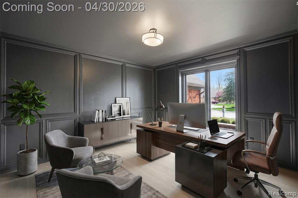 Office space with a decorative wall and light wood-type flooring