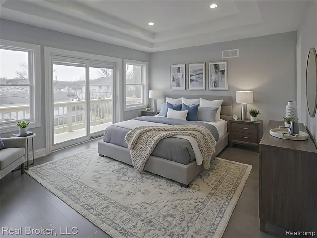 Master Bedroom with a tray ceiling, access to exterior, recessed lighting, and wood flooring