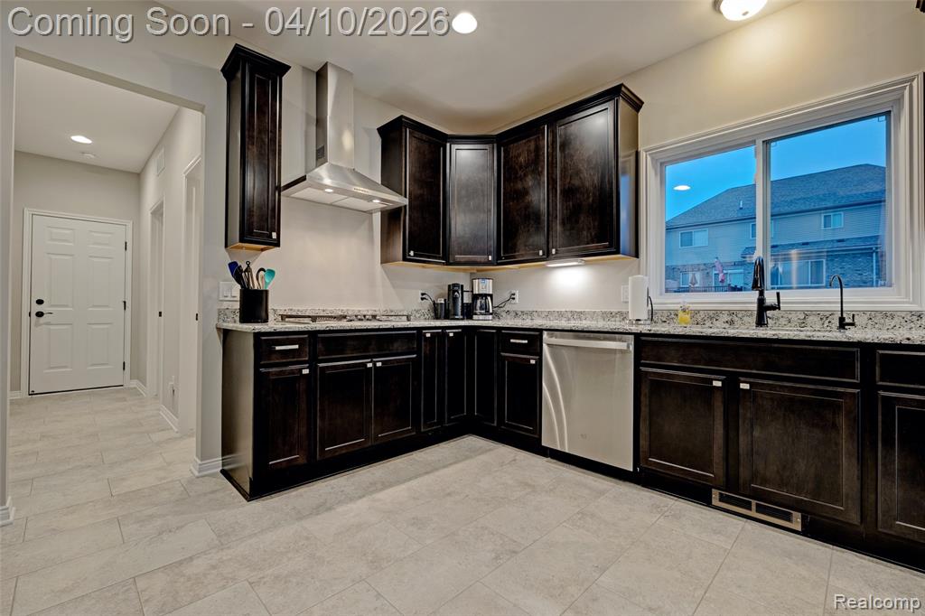 Kitchen with light stone countertops, dishwasher, dark wood finish cabinetry, and recessed lighting