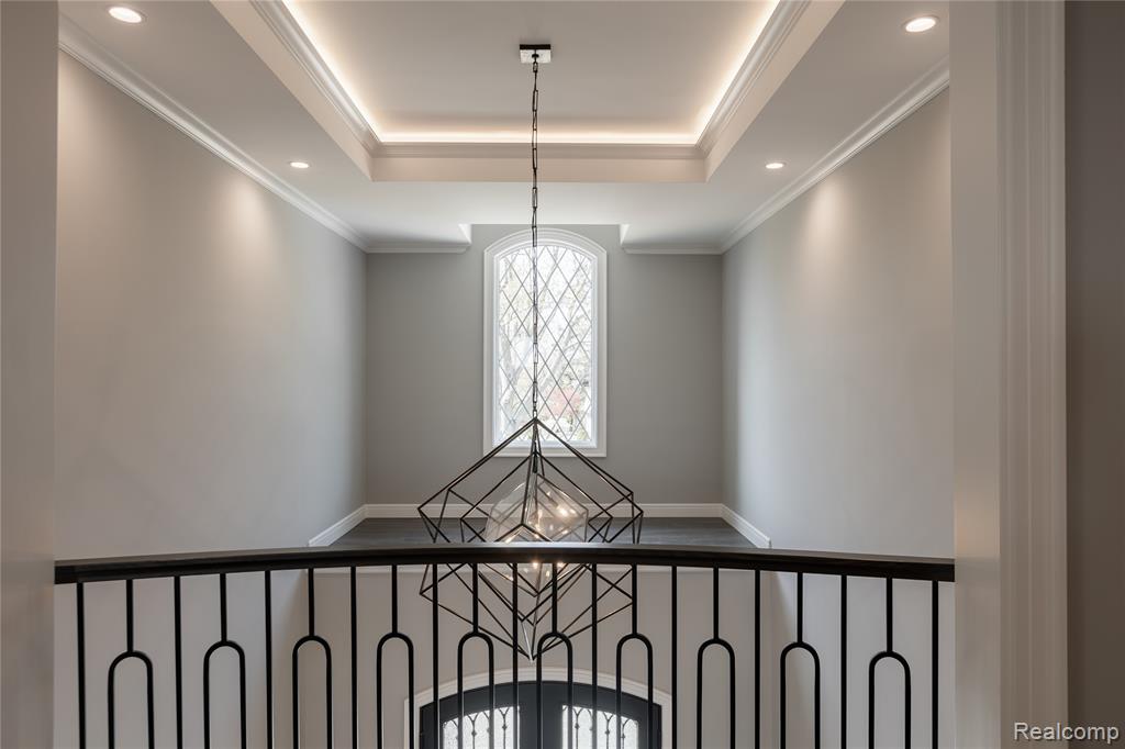 Detailed view of suspended lighting, a tray ceiling, and crown molding