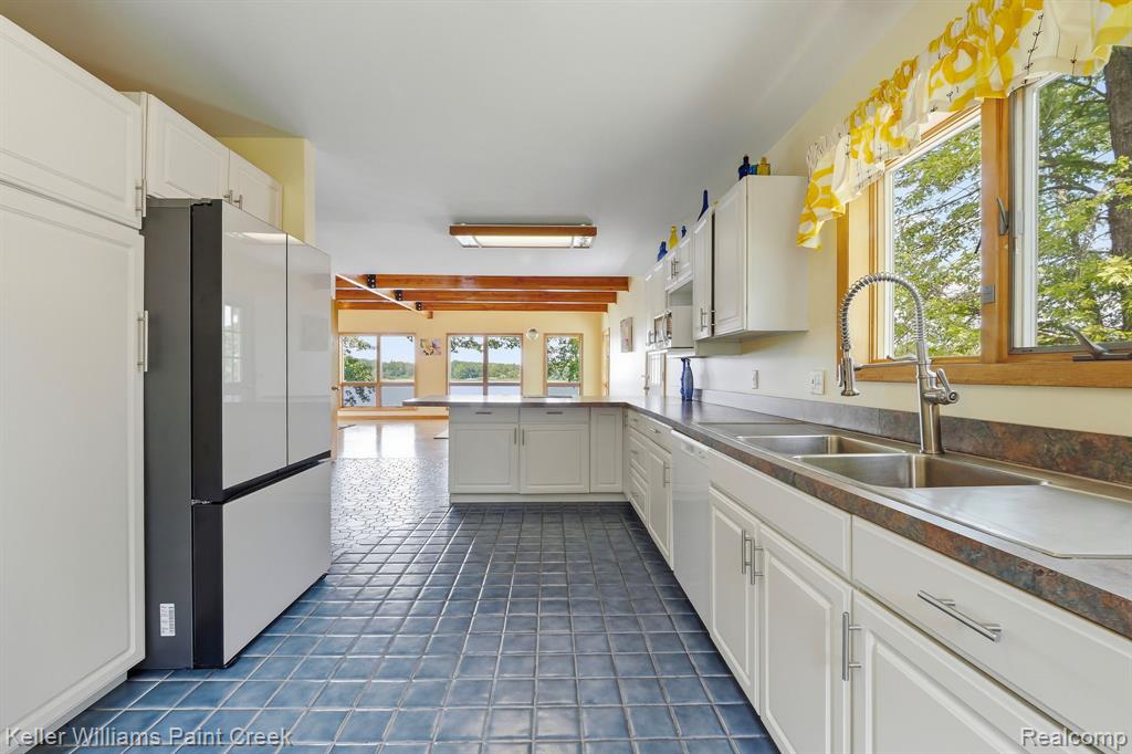 Kitchen featuring white cabinetry, blue tile flooring, a dual-basin sink with a gooseneck faucet, and a built-in refrigerator