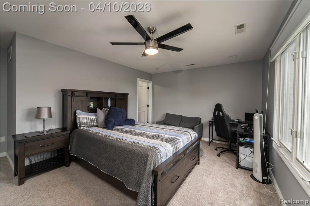 Bedroom featuring an office area, light carpet, and ceiling fan