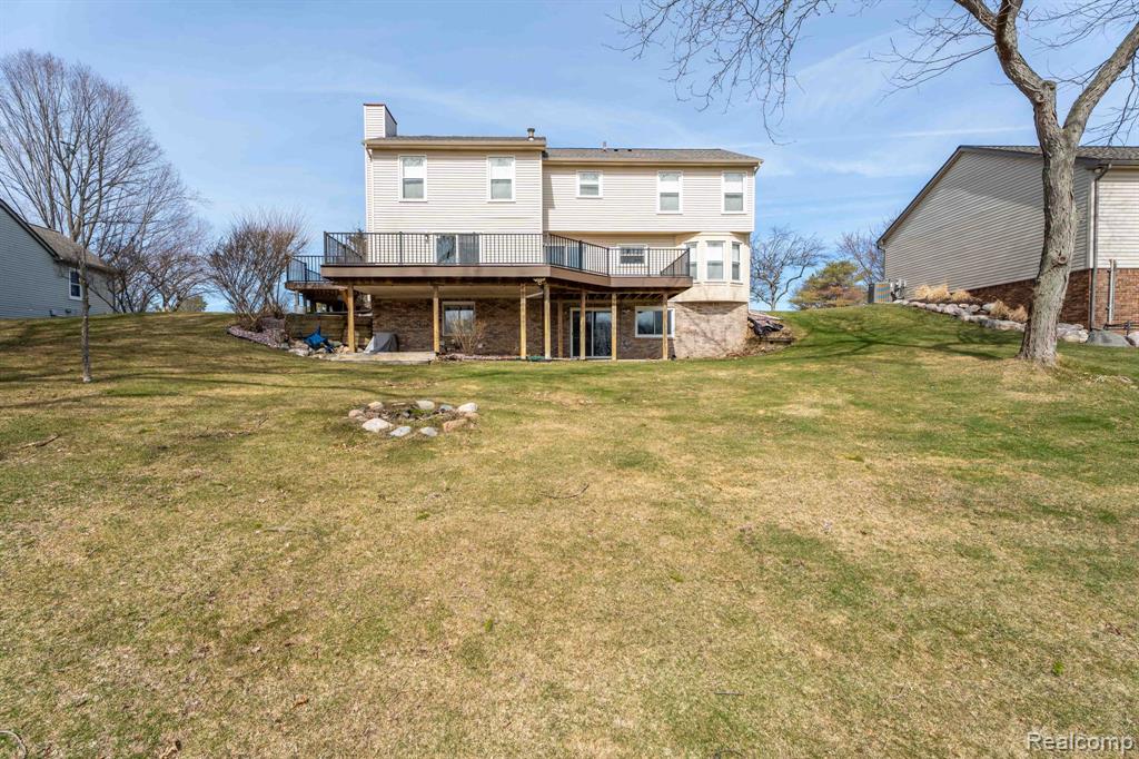 Back of property with a wooden deck, a chimney, and a yard