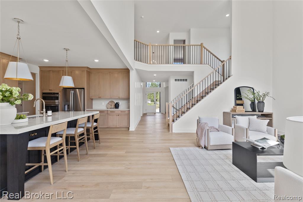 Kitchen with light brown cabinets, stainless steel appliances, light stone countertops, light wood finished floors, and backsplash