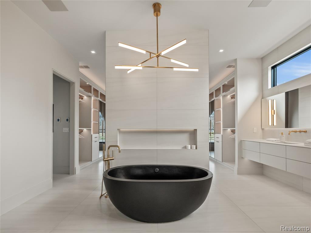 Bathroom with a freestanding bath, a chandelier, light tile patterned floors, vanity, and recessed lighting