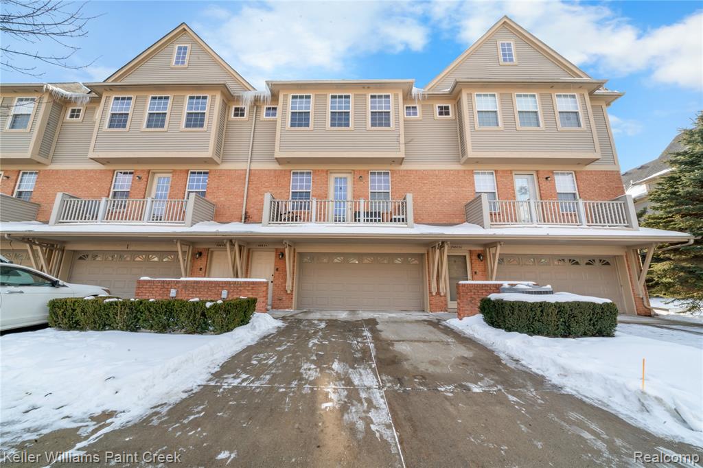 View of front of property featuring a garage, a balcony, and brick siding