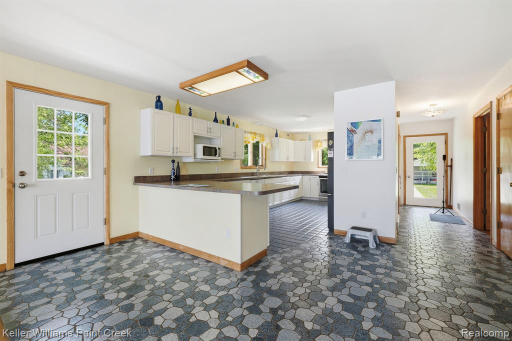 Kitchen with white cabinetry, built-in microwave, and stone-look countertops
