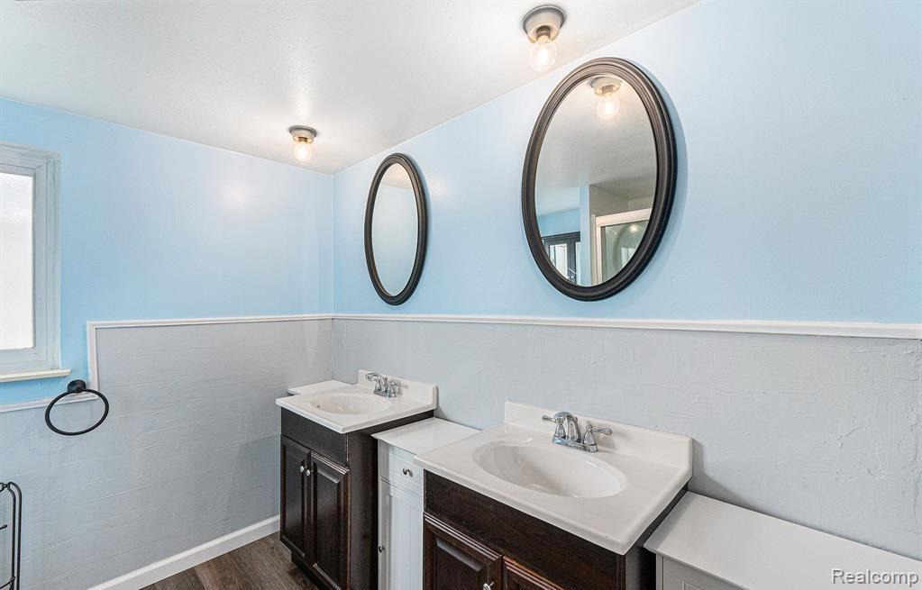 Full bath with two vanities and dark wood finished floors