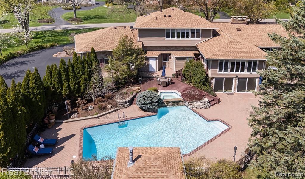 Back of house with a patio, a pool with connected hot tub, and roof with shingles