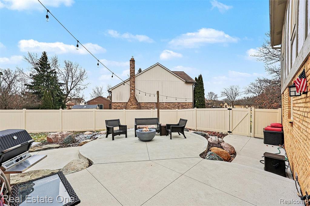 Fenced backyard featuring a patio, a fire pit, and a gate
