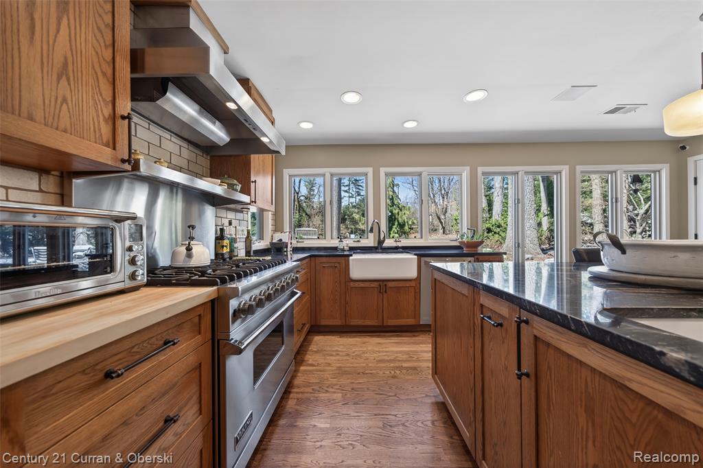 Kitchen featuring designer stove, wood finish cabinets, light wood-type flooring, healthy amount of natural light, and recessed lighting