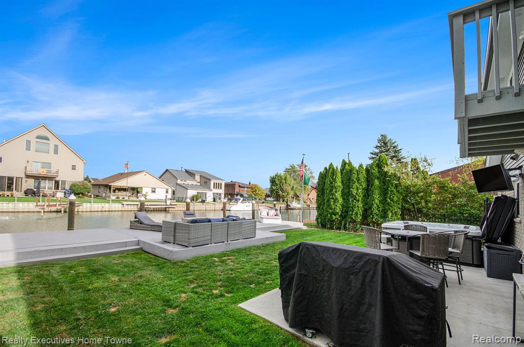 View of grassy yard with outdoor lounge area, a patio, a water view, and a residential view