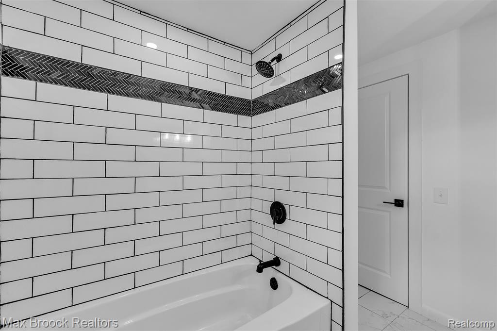 Bathroom featuring shower / tub combination and marble look tile flooring