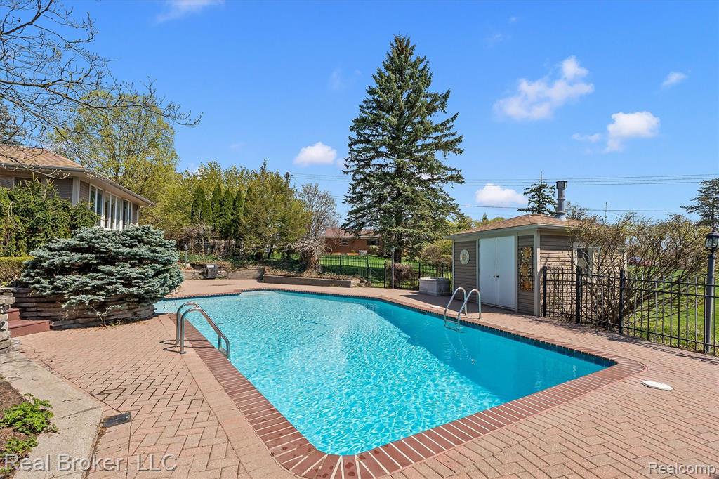View of swimming pool with a fenced backyard, patio surround, and an outbuilding