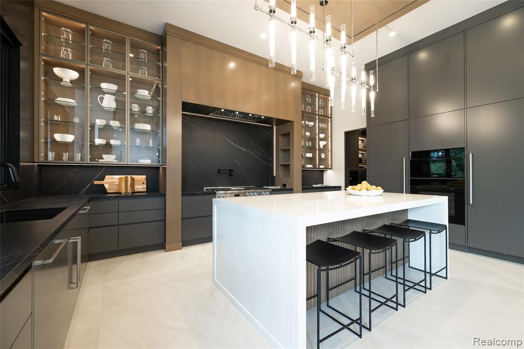 Kitchen with a breakfast bar area, gray cabinets, decorative light fixtures, a kitchen island, and dark stone countertops