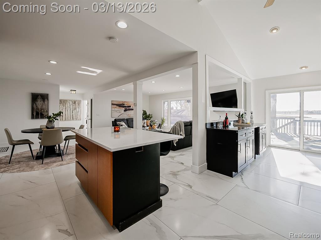 Kitchen featuring dark stone countertops, vaulted ceiling, recessed lighting, and dark cabinetry