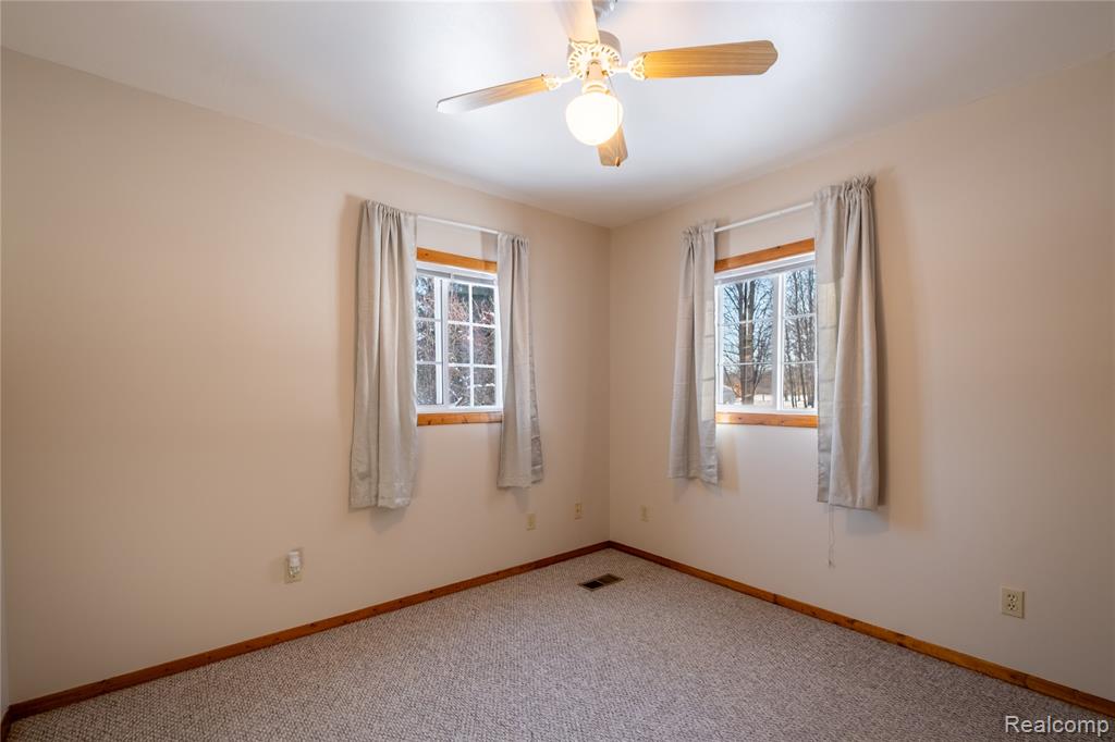 Empty room featuring healthy amount of natural light, carpet floors, and a ceiling fan