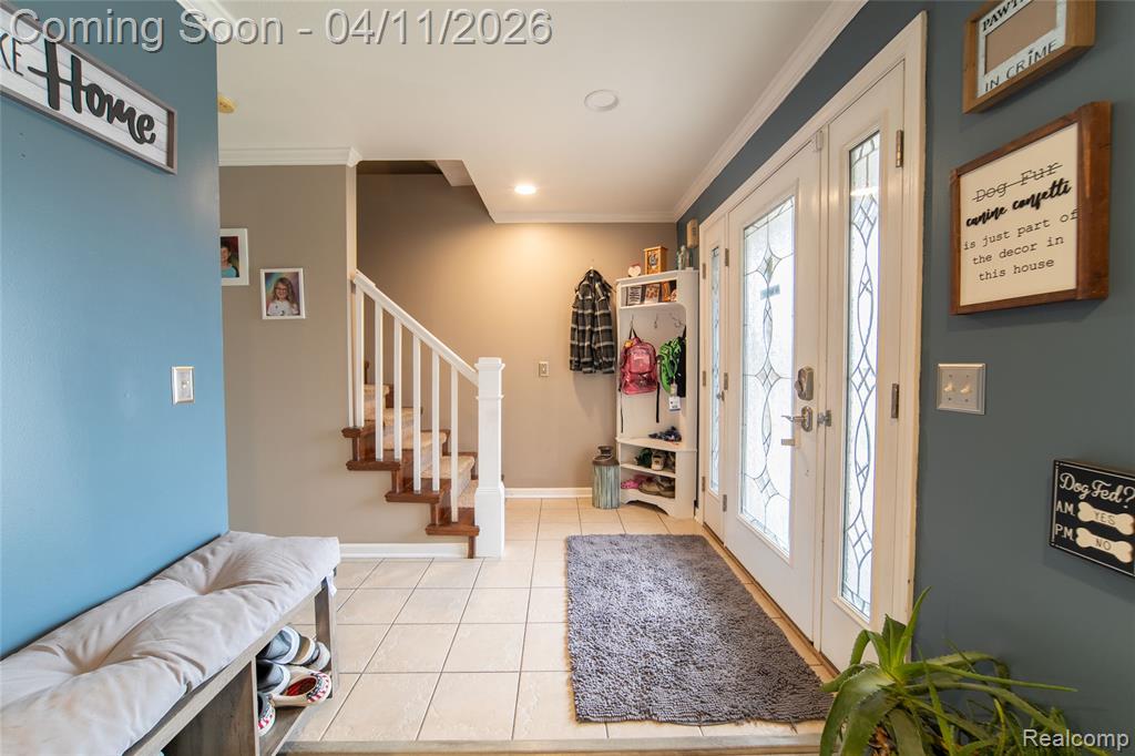 Entrance foyer featuring light tile patterned floors, crown molding, and recessed lighting