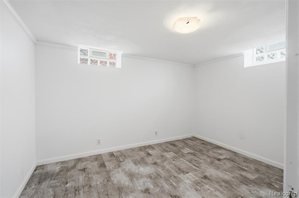 Unfurnished room with light wood-style floors, ornamental molding, and plenty of natural light