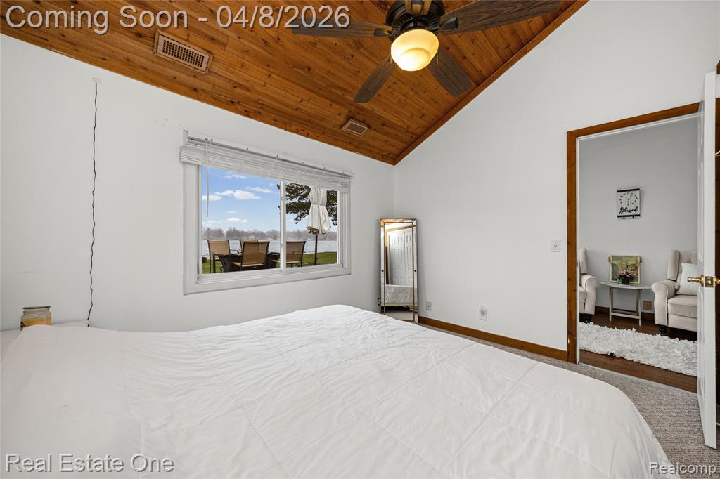 Carpeted bedroom with a ceiling fan and a vaulted wood ceiling