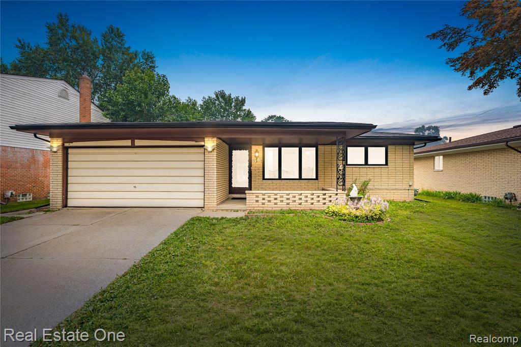 Mid-century modern ranch featuring a brick facade, integrated single-car garage, and a covered entryway