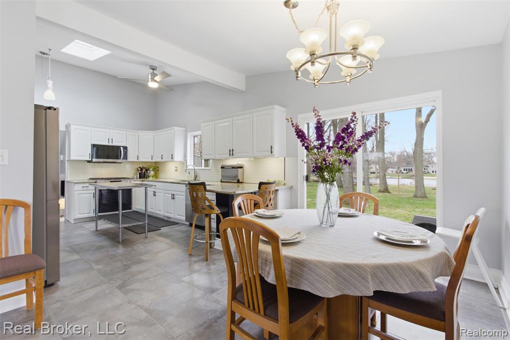 Dining space with ceiling fan, beam ceiling, a skylight, and hanging lights