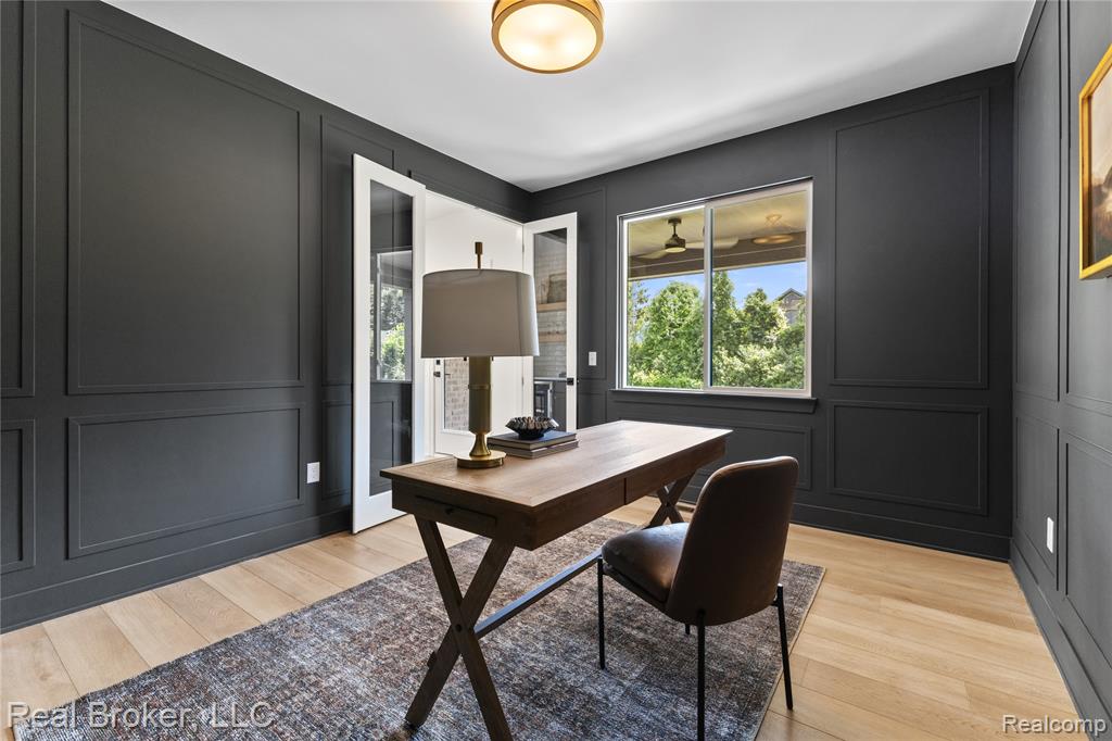 Office with a decorative wall, light wood-style floors, and healthy amount of natural light