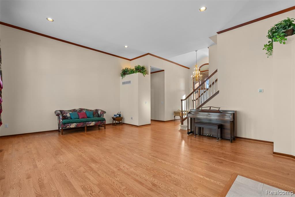 Sitting room featuring light wood finished floors, a chandelier, recessed lighting, stairs, and ornamental molding