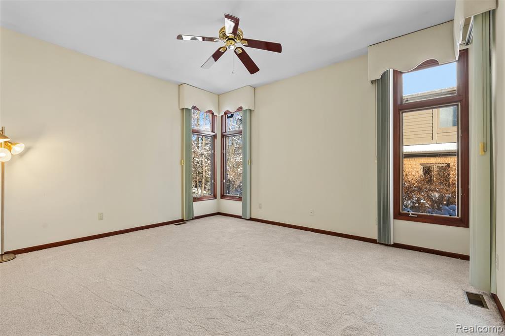Carpeted empty room with baseboards and a ceiling fan