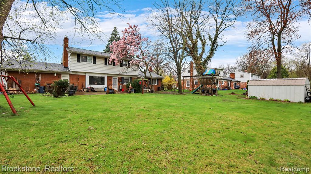 View of green lawn with a playground and a storage shed