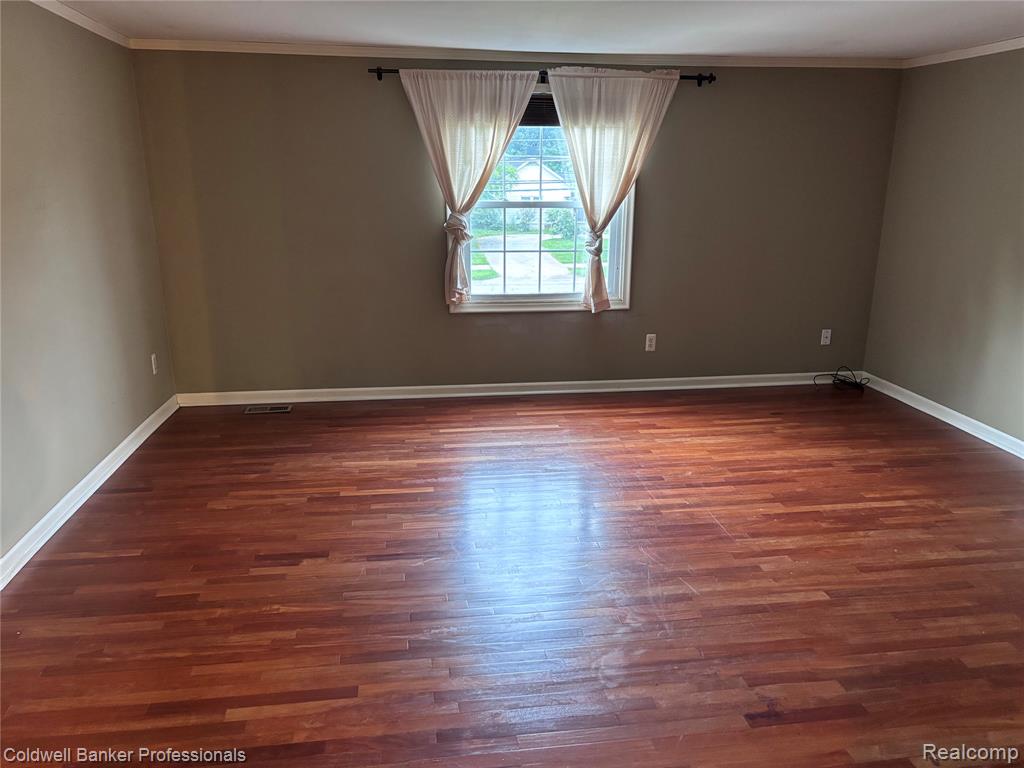 Primary bedroom featuring crown molding and dark wood-style floors