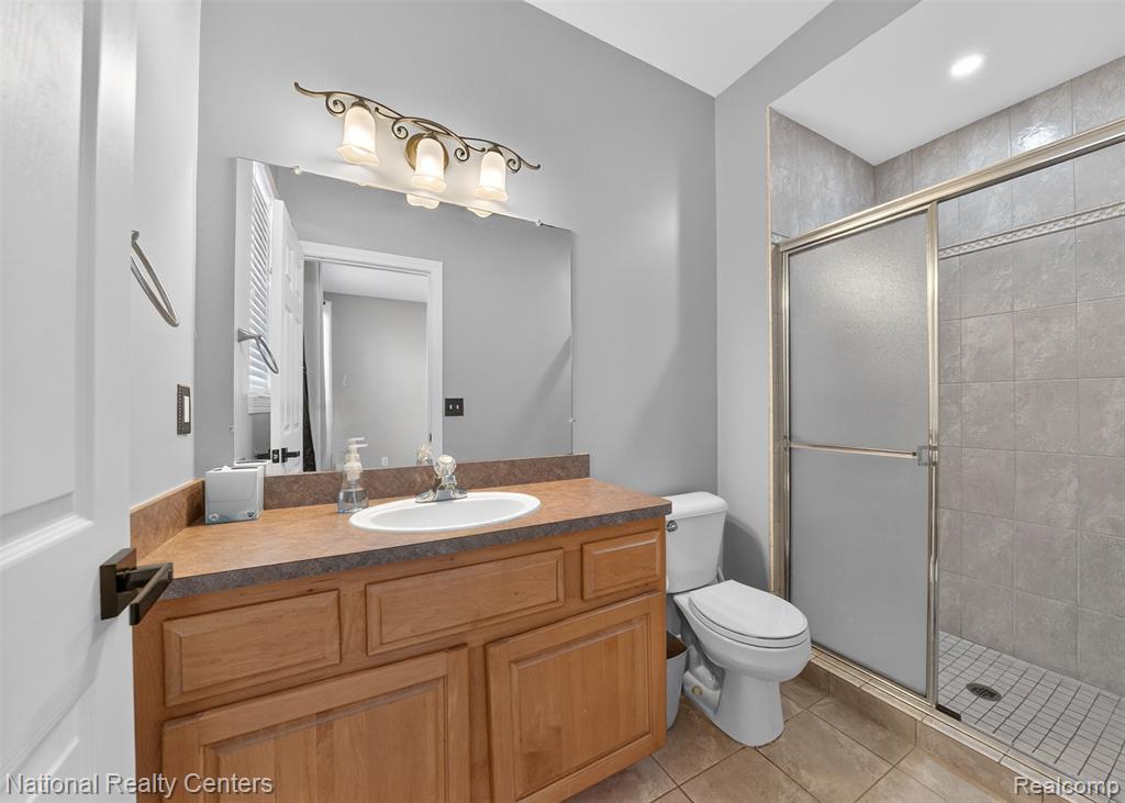 Full bathroom featuring vanity, a stall shower, light tile patterned floors, and recessed lighting