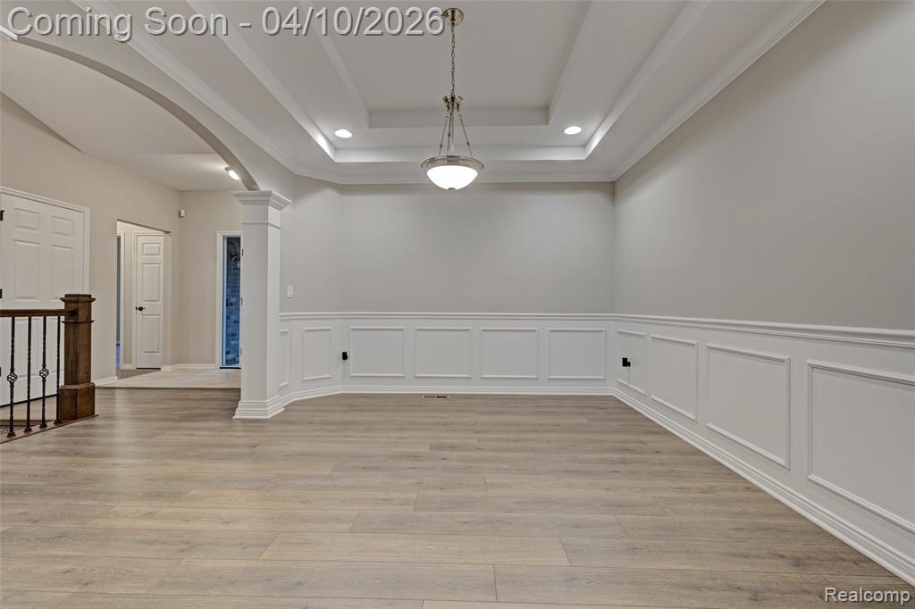 Spare room featuring arched walkways, a decorative wall, a wainscoted wall, light wood finished floors, and recessed lighting